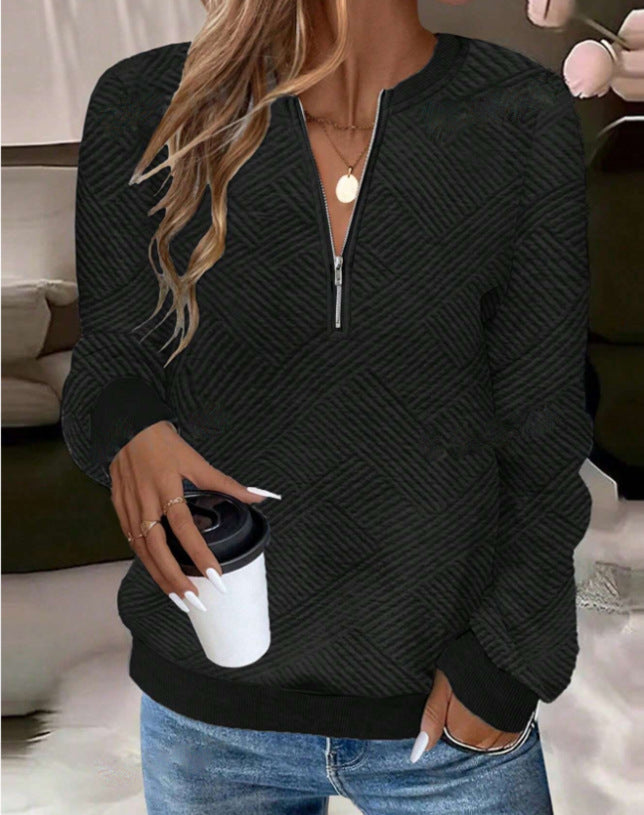 Frau in schwarzem Strickpullover mit Reißverschluss, hält Kaffeebecher. Lässige Mode, Herbstoutfit, gemütlicher Stil, blonde Haare, Jeans.