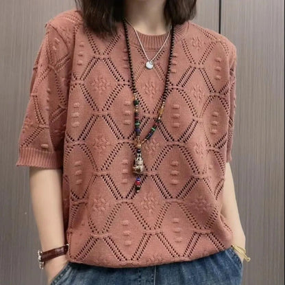Frau trägt rosa Strickpullover mit geometrischem Muster und Halsketten, kombiniert mit blauen Jeans. Modetrend, Damenmode, Strickmode.
