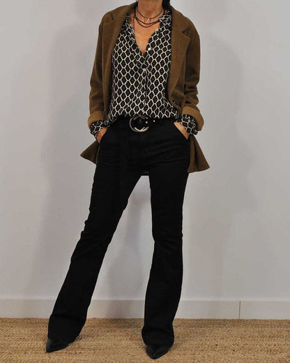 Frau in modischem Outfit mit braunem Blazer, gemusterter Bluse und schwarzer Hose. Stilvolle Herbstmode, Business-Casual-Look, Damenbekleidung.