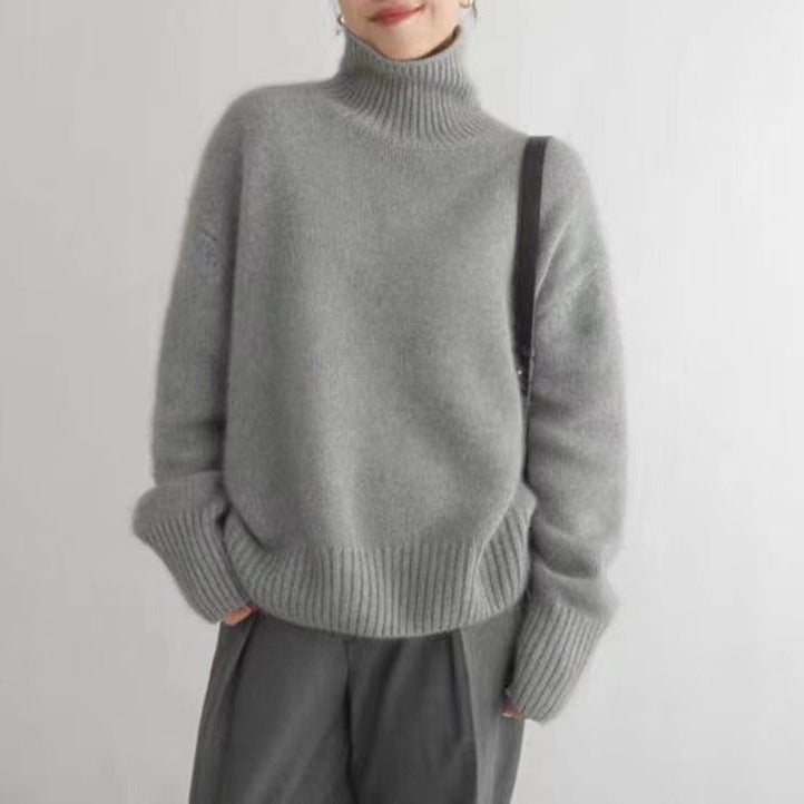 Grauer Rollkragenpullover aus Kaschmir, getragen von einer Person, kombiniert mit grauer Hose. Modischer, gemütlicher Winterlook.