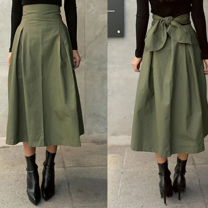 Damen A-Linien-Rock in Olivgrün, knielang, mit hoher Taille und Schleifendetail hinten. Perfekt für Herbstmode, kombiniert mit schwarzen Stiefeletten.