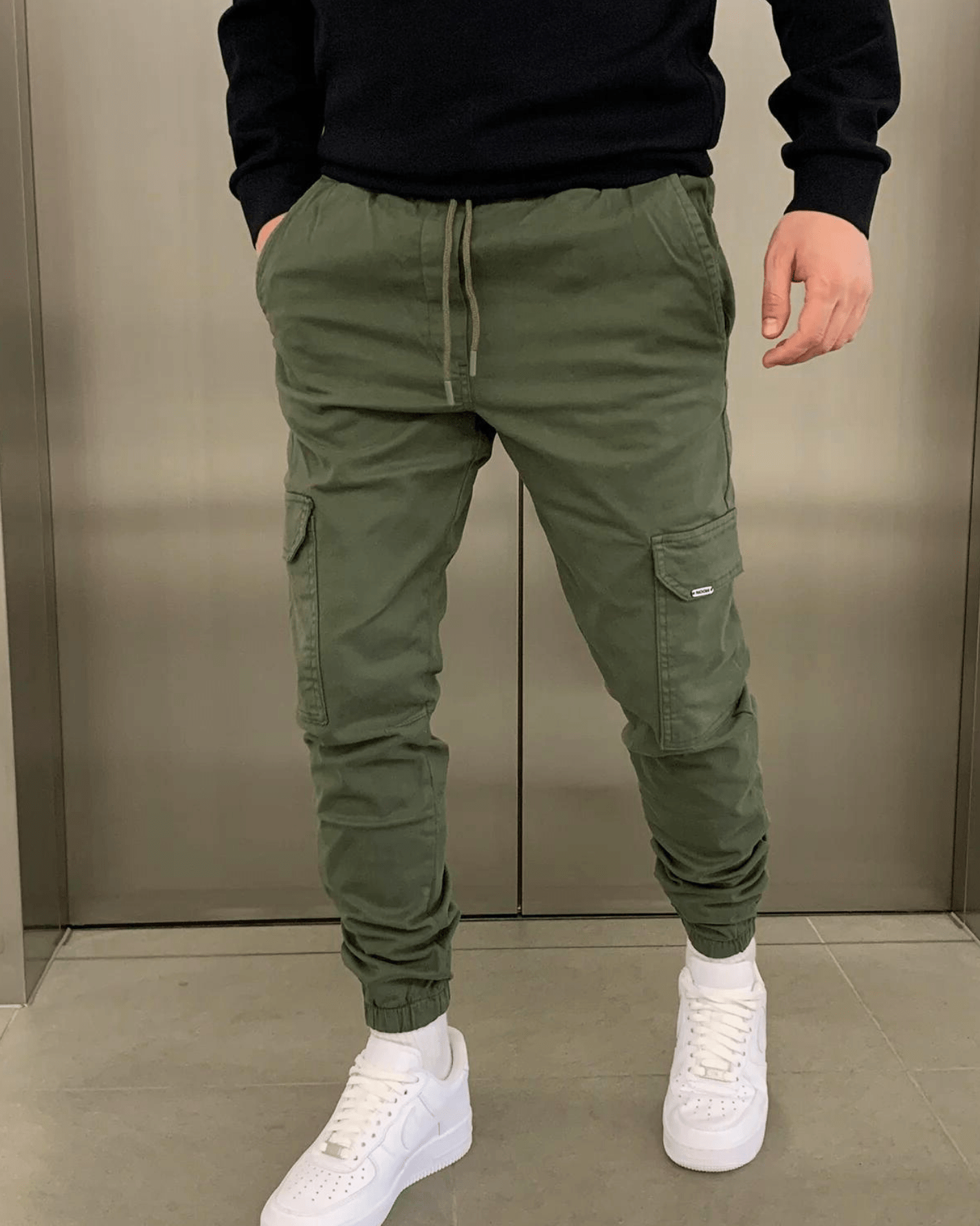 Grüne Cargo-Jogginghose für Herren, kombiniert mit weißen Sneakers. Bequeme Freizeitmode, ideal für lässigen Streetwear-Look.