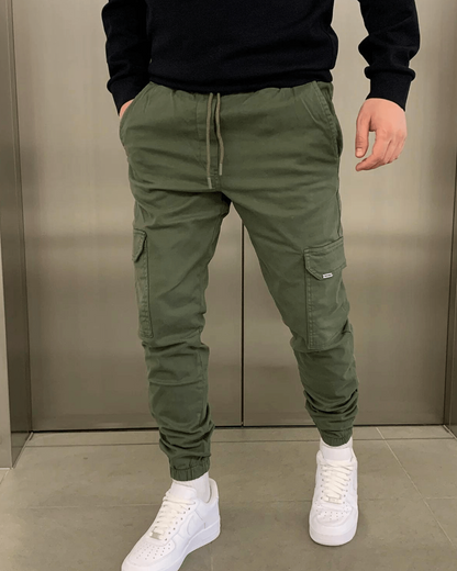 Grüne Cargo-Jogginghose für Herren, kombiniert mit weißen Sneakers. Bequeme Freizeitmode, ideal für lässigen Streetwear-Look.