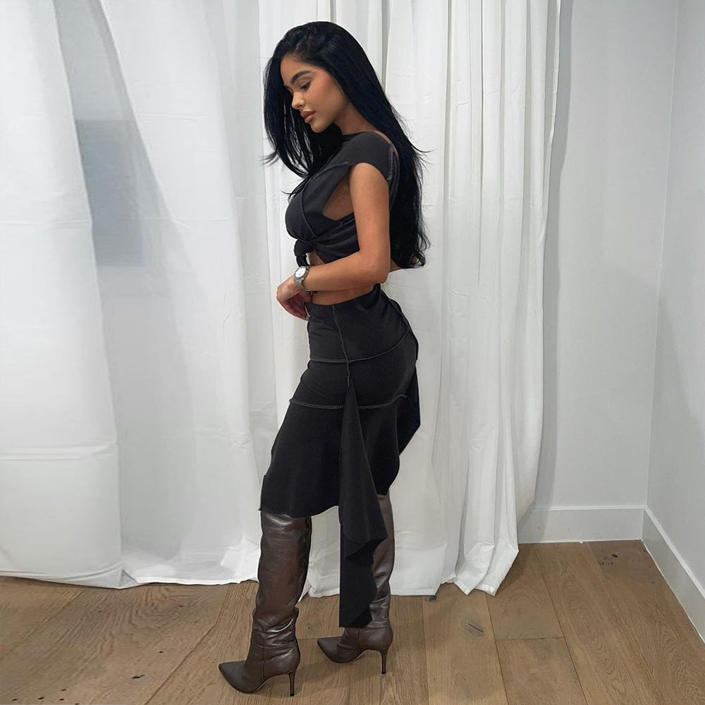 Frau in elegantem schwarzen Kleid und braunen Stiefeln posiert vor weißen Vorhängen auf Holzboden. Mode, Stil, Abendkleid, Damenmode.