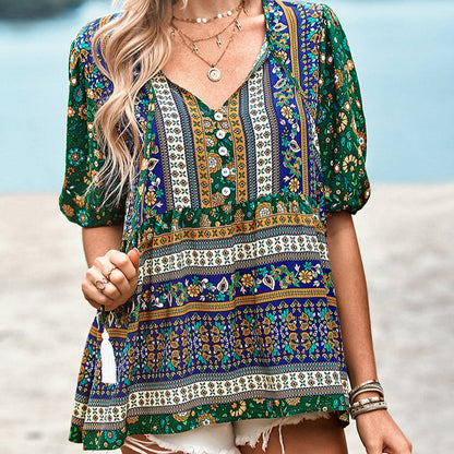 Frau trägt buntes Boho-Kleid mit Blumenmuster, V-Ausschnitt und kurzen Ärmeln am Strand. Sommermode, Boho-Stil, Damenbekleidung.
