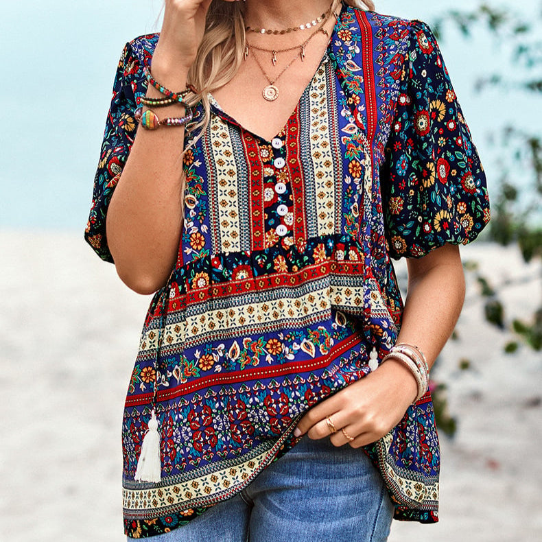 Frau trägt bunte Boho-Bluse mit ethnischem Muster und V-Ausschnitt, kombiniert mit blauen Jeans. Perfekt für Sommermode und Freizeitoutfits.