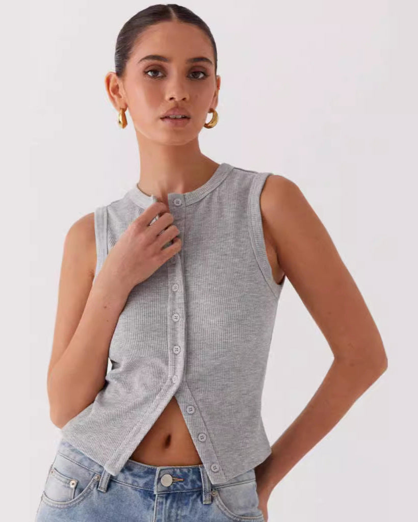 Frau trägt graues ärmelloses Stricktop mit Knopfleiste, kombiniert mit blauen Jeans. Modetrend, Damenbekleidung, lässiger Stil.