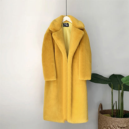 Gelber Kunstpelzmantel auf Kleiderbügel, langer Schnitt, weiches Material, modisch und warm, ideal für Wintermode, hängend vor neutralem Hintergrund.
