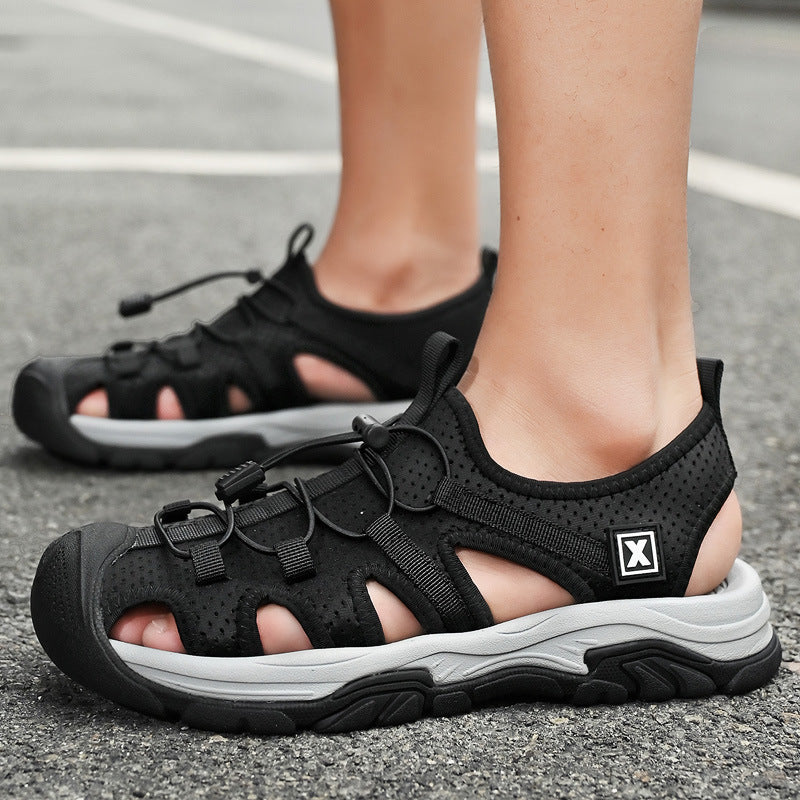 Schwarze Outdoor-Sandalen mit robustem Design, atmungsaktivem Material und rutschfester Sohle auf Asphalt. Ideal für Wandern und Freizeit.
