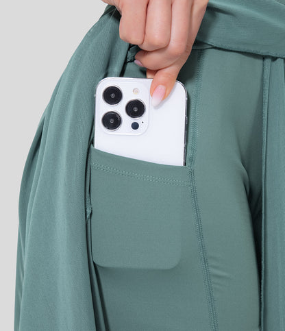 Hand hält ein weißes Smartphone mit drei Kameras in der Tasche einer grünen Sporthose. Moderne Technologie, Smartphone, Sportbekleidung.