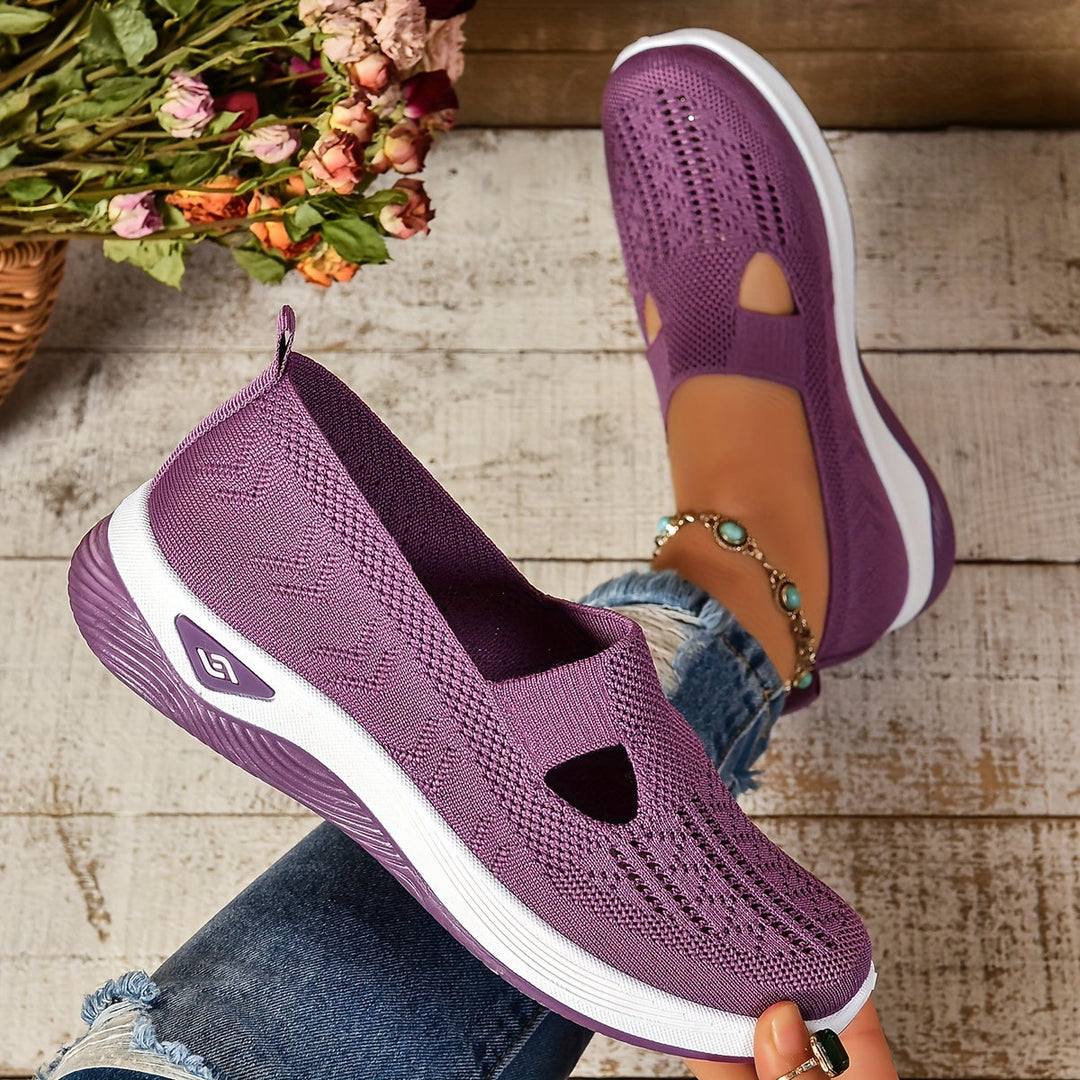 Lila Damen-Sneaker aus Strickmaterial, atmungsaktiv und leicht, auf weißem Holzboden. Perfekt für Freizeit und Sommermode.
