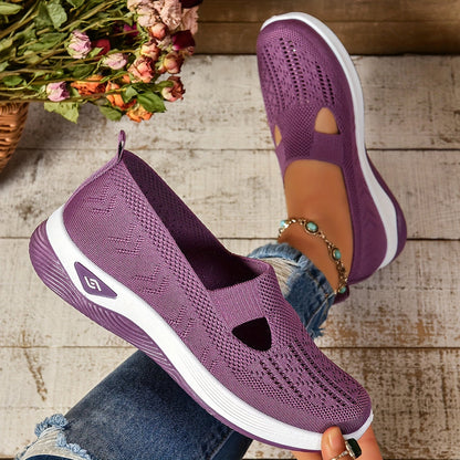 Lila Damen-Sneaker aus Strickmaterial, atmungsaktiv und leicht, auf weißem Holzboden. Perfekt für Freizeit und Sommermode.