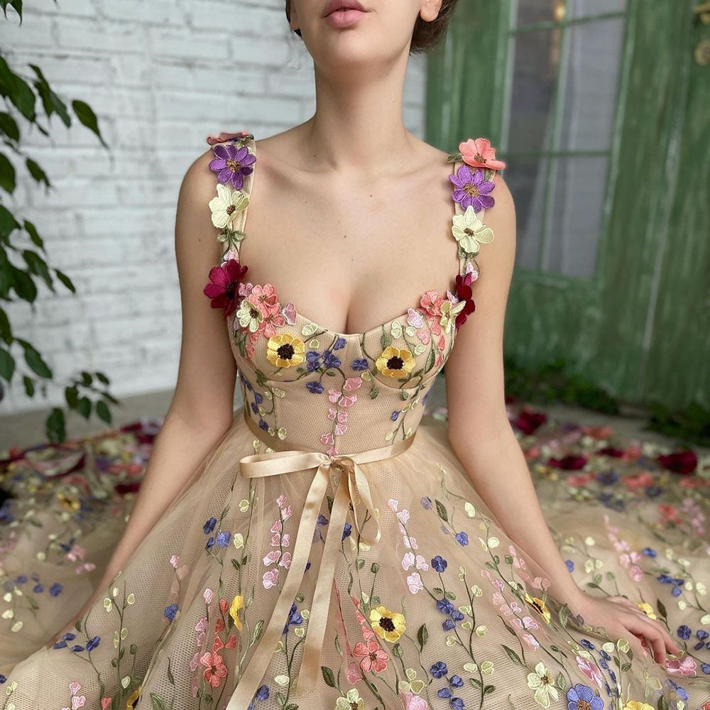 Frau in einem eleganten, blumengeschmückten Kleid vor grüner Tür. Stickereien mit bunten Blumen, romantischer Look, modisches Design.
