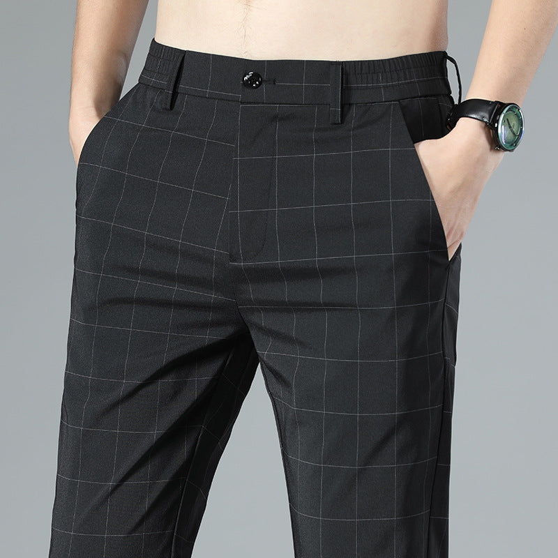 Mann trägt schwarze karierte Anzughose mit Händen in den Taschen, Armbanduhr am Handgelenk. Elegante Herrenmode, Business-Look.