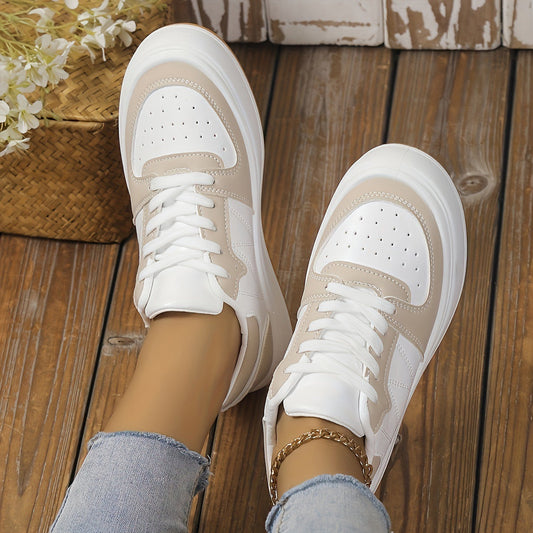 Beige-weiße Sneaker auf Holzboden, getragen von Person in blauen Jeans. Modische Damen-Schuhe, Freizeit-Look, trendige Sneaker für Alltag.