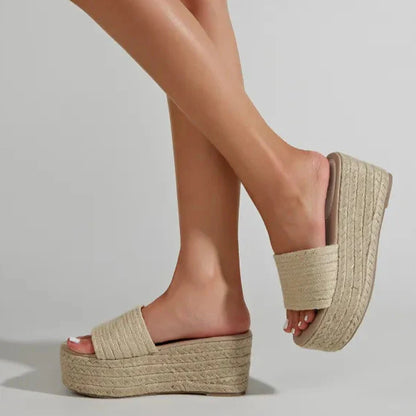 Damenbeine in beigen Plateau-Sandalen aus Bast, Sommermode, trendige Schuhe, bequem, elegant, ideal für Strand und Freizeit, modischer Look.