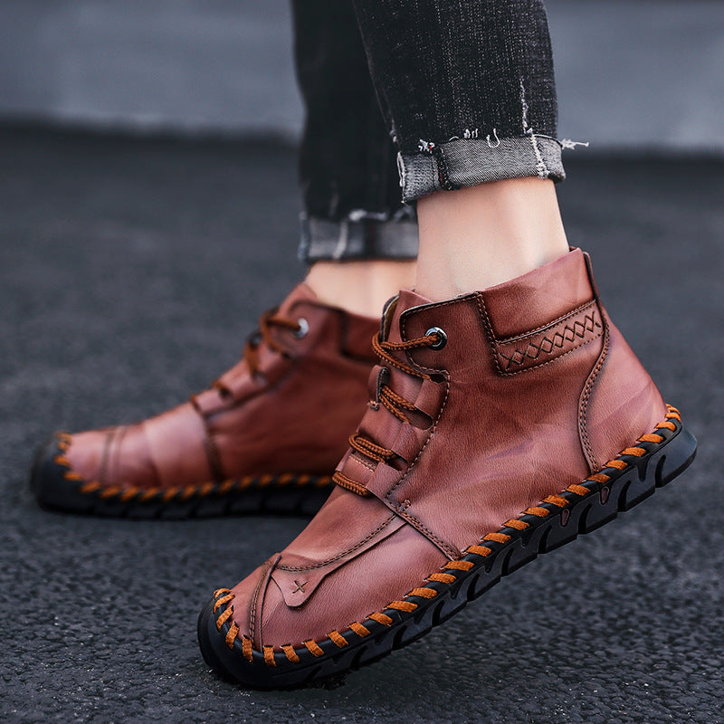 Braune Herren-Lederstiefel mit schwarzer Sohle, handgenäht, lässiger Stil, getragen auf Asphalt. Modische, bequeme Schuhe für den Alltag.