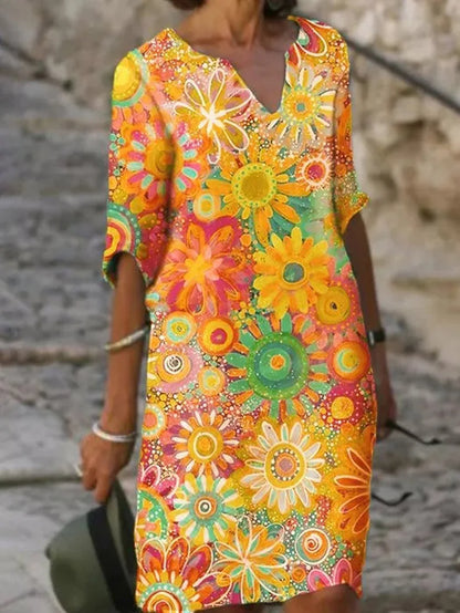 Frau in buntem, geblümtem Sommerkleid mit leuchtenden Farben und Blumenmuster, steht auf gepflastertem Weg. Modetrend, Sommermode, Damenkleid.