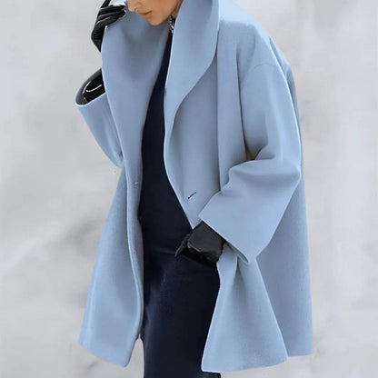 Dame in hellblauem Oversize-Mantel, schwarzer Kleidung und Handschuhen. Modetrend, eleganter Winterlook, stilvolle Damenbekleidung.