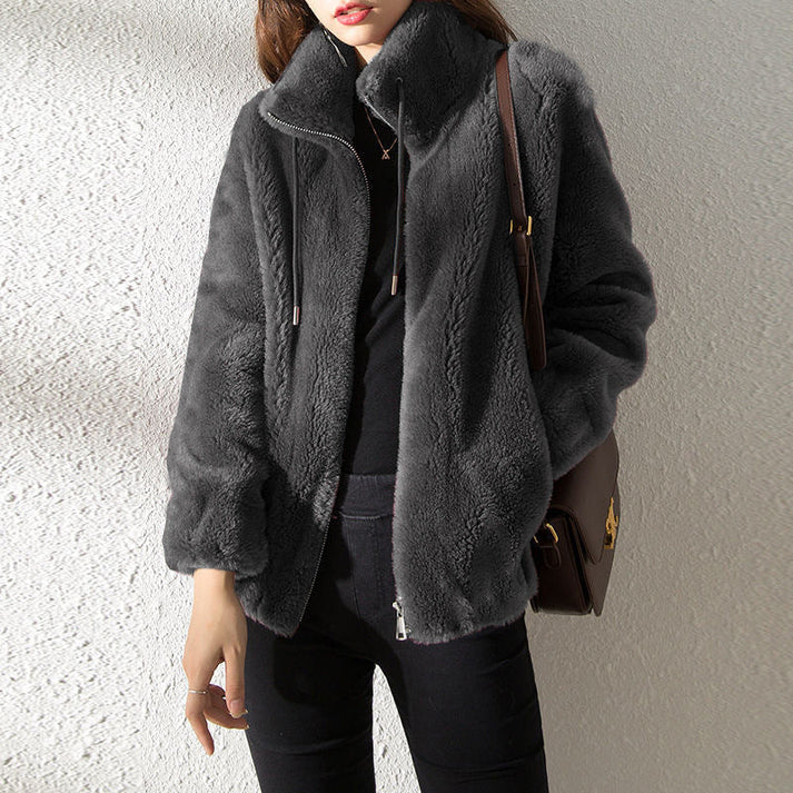 Dunkelgraue Kunstpelzjacke für Damen, modisch und warm, ideal für Herbst und Winter. Perfekt kombiniert mit schwarzer Hose und brauner Tasche.