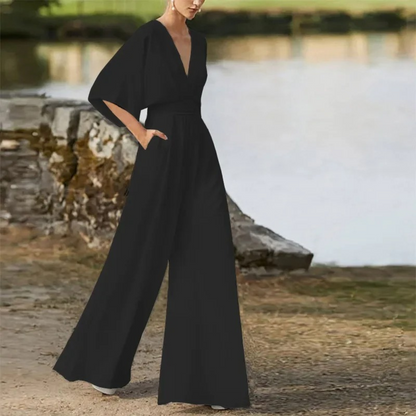 Eleganter schwarzer Jumpsuit mit weitem Bein und tiefem V-Ausschnitt, getragen von einer Frau im Freien. Modetrend, stilvolle Damenbekleidung.