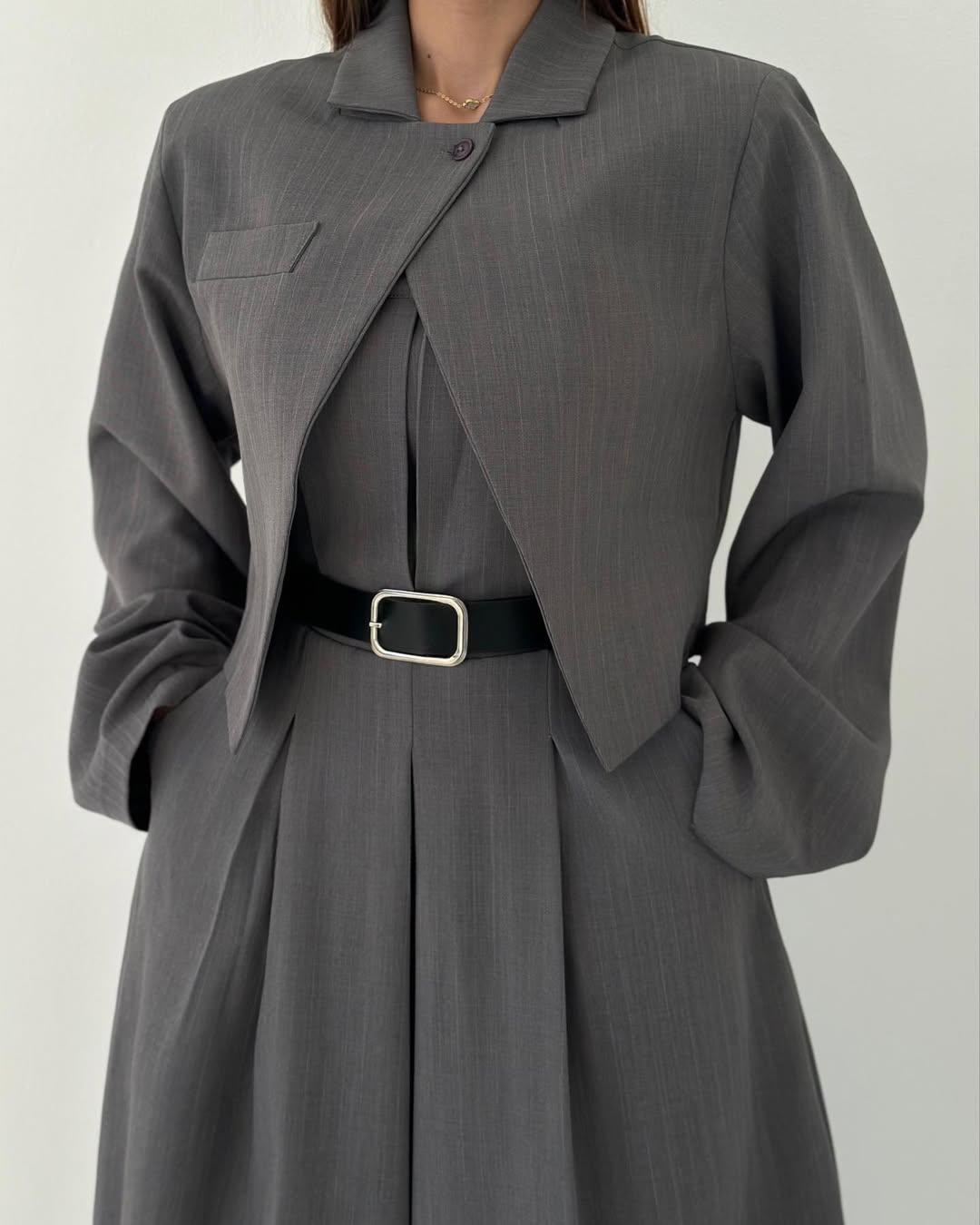 Frau in grauem Anzugkleid mit Gürtel, elegantes Business-Outfit, moderne Damenmode, stilvolle Bürobekleidung, minimalistisch, zeitloses Design.