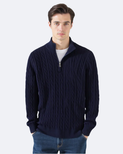 Junger Mann trägt dunkelblauen Zopfmuster-Pullover mit Reißverschluss, kombiniert mit blauer Jeans. Elegante Herrenmode, Winteroutfit, Strickpullover.