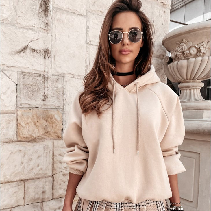 Frau in beigem Hoodie und Sonnenbrille vor Steinwand, modisch, urbaner Stil, Herbstmode, lässiger Look, Streetwear, Modeaccessoires.