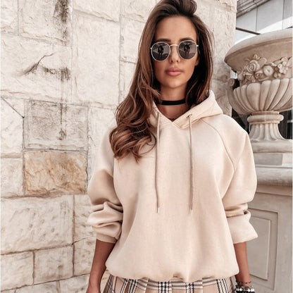 Frau in beigem Hoodie und Sonnenbrille vor Steinwand, modisch, urbaner Stil, Herbstmode, lässiger Look, Streetwear, Modeaccessoires.