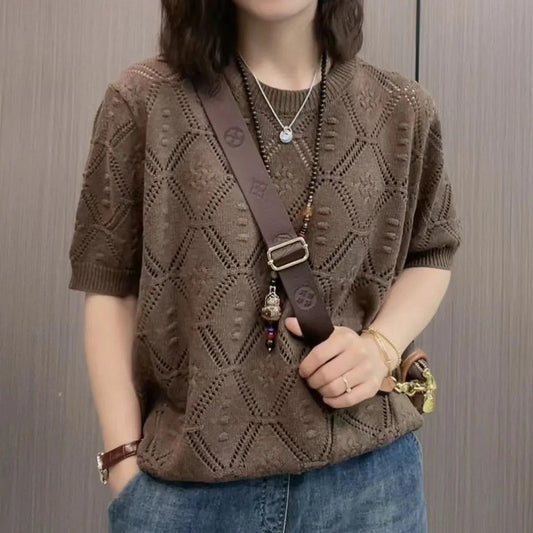 Frau in braunem Strickpullover mit geometrischem Muster, trägt Umhängetasche und Jeans. Modetrend, Strickmode, lässiger Stil.