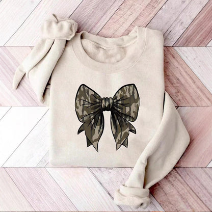 Beiges Sweatshirt mit großem Camouflage-Schleifen-Design auf Holzfußboden. Modetrend, lässiger Stil, Damenbekleidung, urbaner Look.