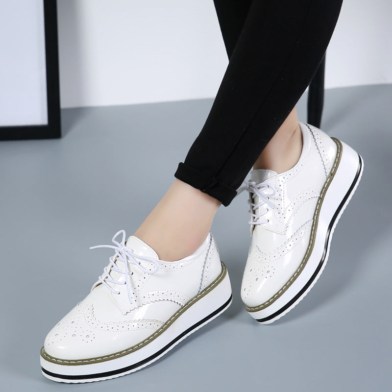 Weiße Damen-Brogues mit Plateau, geschnürt, perforiertes Design, getragen mit schwarzen Leggings. Modische Schuhe, ideal für trendbewusste Outfits.