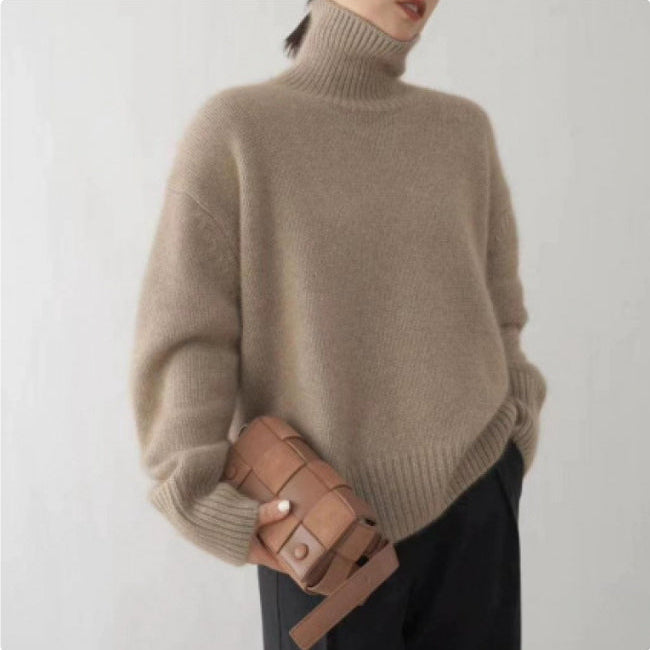 Frau in beigem Rollkragenpullover hält braune Lederhandtasche, minimalistisch, modisch, Herbstmode, eleganter Stil, neutrale Farben.