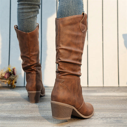 Damenstiefel aus braunem Leder mit Blockabsatz, getragen zu blauen Jeans. Modische Herbst- und Winterstiefel für Damen, ideal für Freizeitoutfits.