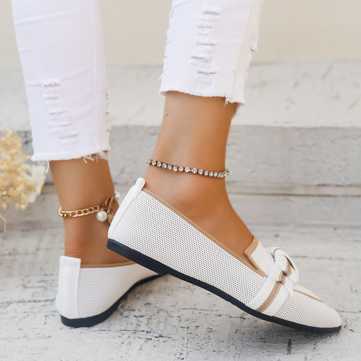 Weiße Damen-Loafer mit Schleife, getragen zu zerrissenen weißen Jeans. Elegante Sommermode, flache Schuhe, stilvoller Look für Frauen.