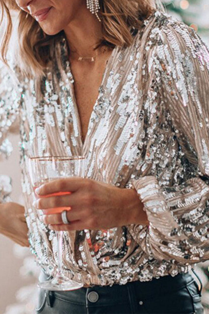Frau in glitzernder Paillettentop, hält ein Glas, trägt elegante Ohrringe und Ring. Perfekt für festliche Mode, Party-Outfit, glamouröser Look.