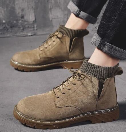 Beige Herren-Wildlederstiefel mit dicker Sohle und Schnürung, kombiniert mit hochgekrempelten Jeans. Modische, robuste Herbst- und Winterstiefel.