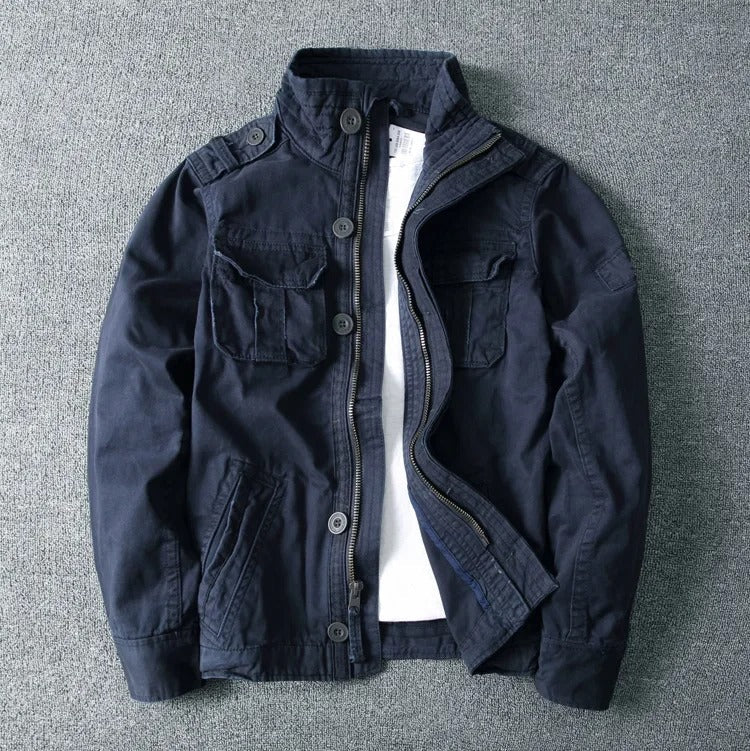 Dunkelblaue Herrenjacke mit Stehkragen, Knopfleiste und mehreren Taschen auf grauem Hintergrund. Modische Freizeitjacke für Männer.