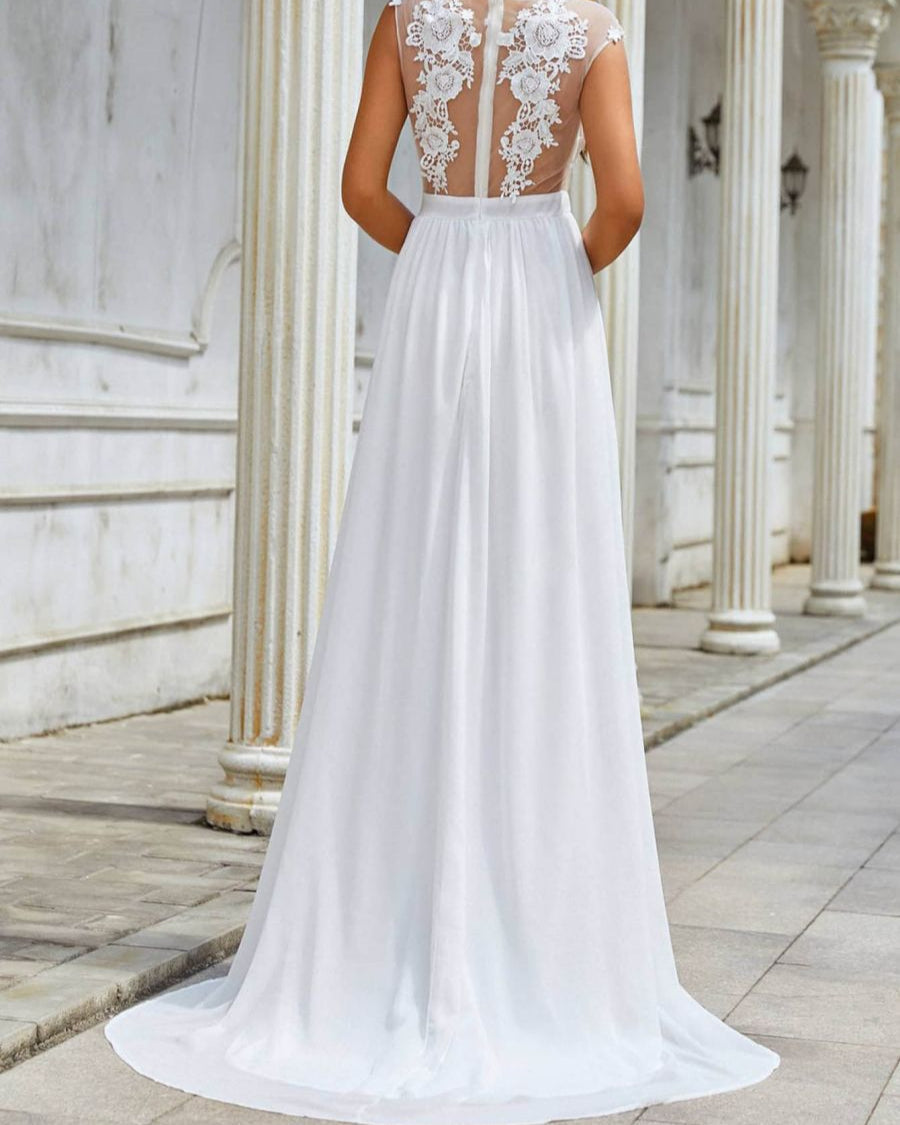Brautkleid mit Spitze und transparentem Rücken, bodenlang, vor weißen Säulen. Elegantes Hochzeitskleid, romantisches Design, klassische Architektur.
