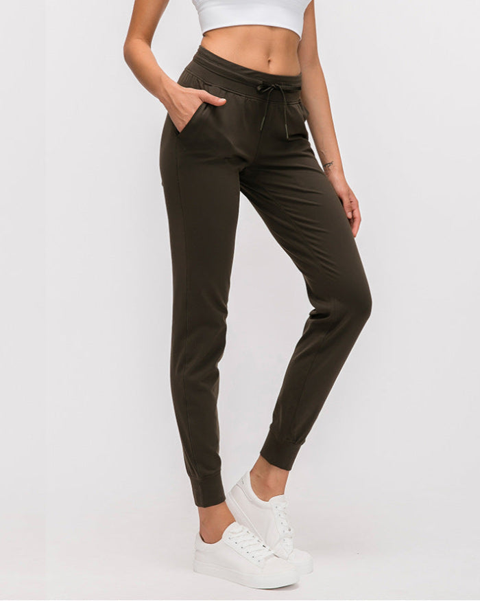 Frau in olivgrüner Jogginghose und weißem Crop-Top, trägt weiße Sneaker. Bequeme Sportbekleidung, ideal für Fitness und Freizeit.