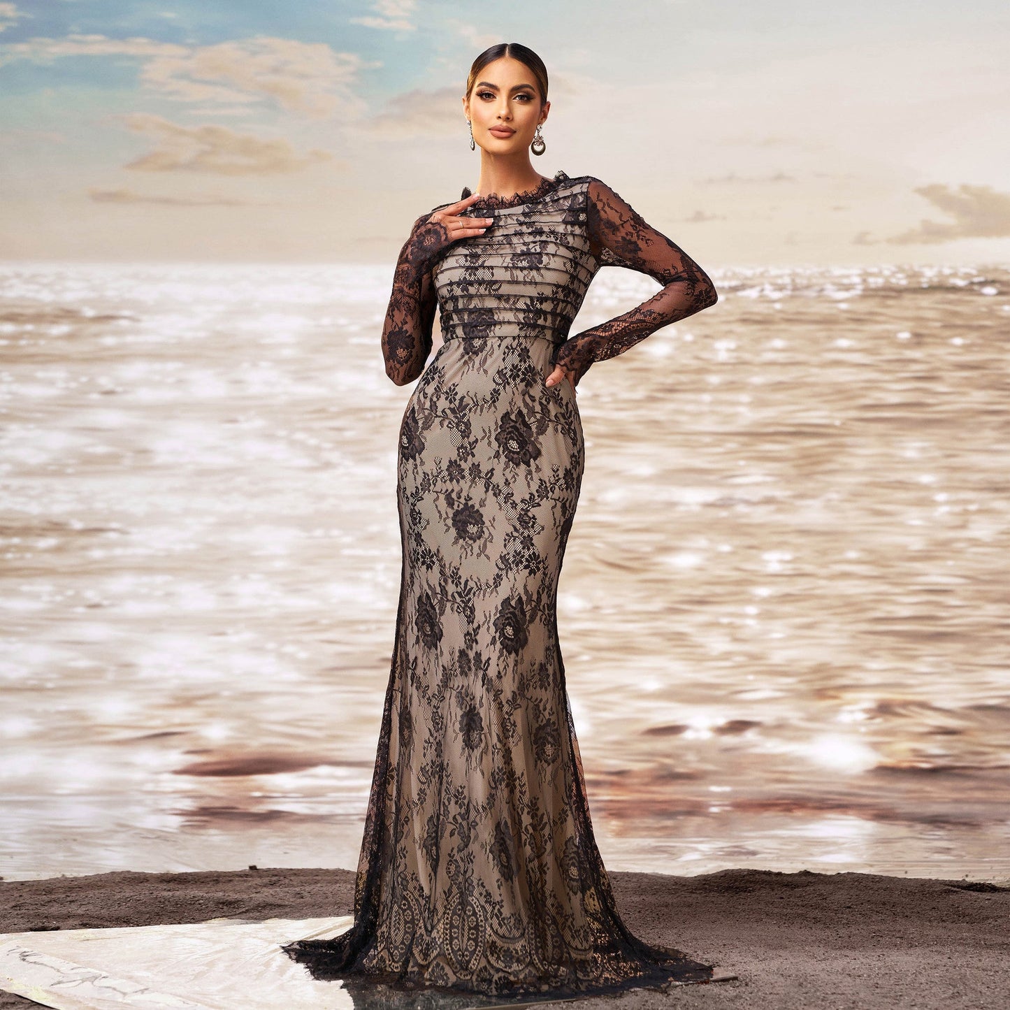 Elegante Frau in langem, schwarzem Spitzenkleid am Strand bei Sonnenuntergang, Modefotografie, Abendkleid, stilvolle Abendmode, glamouröses Design.