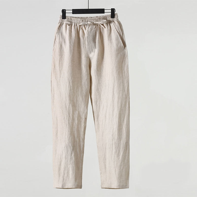 Beige Leinenhose auf Kleiderbügel, minimalistisch, lässig, atmungsaktiv, ideal für Sommermode, Unisex-Design, elastischer Bund, seitliche Taschen.