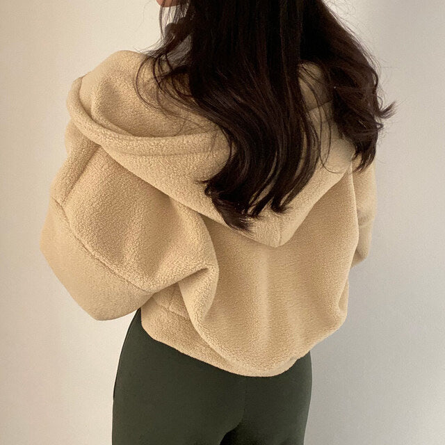 Frau in beiger Teddyjacke mit Kapuze, Rückansicht. Modetrend Herbst/Winter, kuscheliger Fleece-Stoff, lässiger Stil. Ideal für kalte Tage.