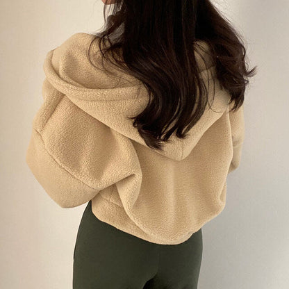 Frau in beiger Teddyjacke mit Kapuze, Rückansicht. Modetrend Herbst/Winter, kuscheliger Fleece-Stoff, lässiger Stil. Ideal für kalte Tage.