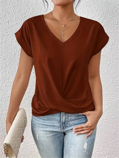 Frau in braunem V-Ausschnitt-Shirt und blauer Jeans, hält weiße gesteppte Clutch. Modetrend, lässiger Look, Damenmode, Streetstyle.