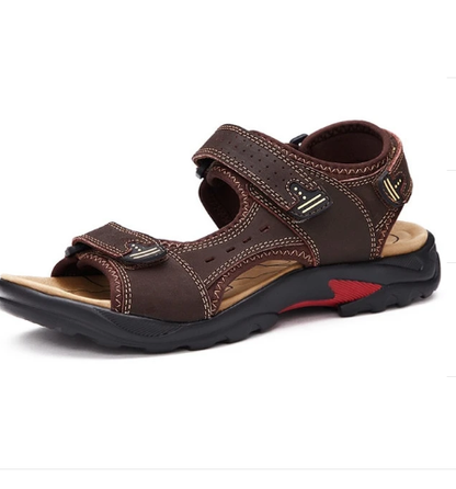Braune Herrensandale mit Klettverschluss, robustem Profil und rotem Akzent. Ideal für Outdoor-Aktivitäten. Bequeme, atmungsaktive Sommerschuhe.