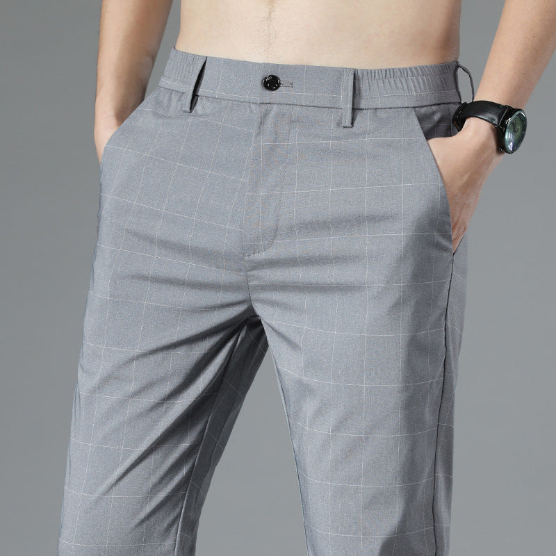 Graue karierte Herrenhose, moderne Passform, mit schwarzem Knopf und Taschen, getragen von einem Mann mit schwarzer Armbanduhr.