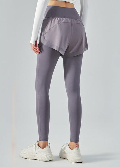 Frau in grauen Leggings mit Shorts, weißem Langarmshirt und weißen Sneakers. Sportbekleidung, Fitnessmode, bequeme Damenoutfits.