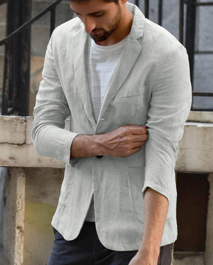 Mann in grauem Leinenblazer, lässig über weißem T-Shirt, zieht Ärmel hoch. Stilvolle Herrenmode, urbaner Look, Freizeitkleidung.