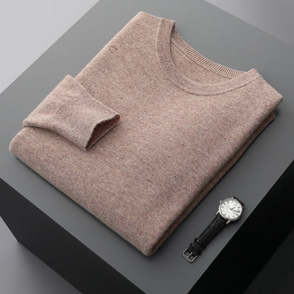 Beigefarbener Kaschmirpullover auf grauem Tisch neben eleganter Armbanduhr. Hochwertige Mode, luxuriöse Materialien, stilvolle Accessoires.